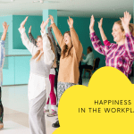 4 women with hands in the air laughing for happiness in the workplace