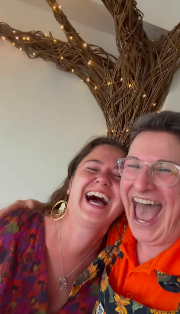 Sunny Turner and a colleague laughing together under fairy lights at a Serious Laughter event
